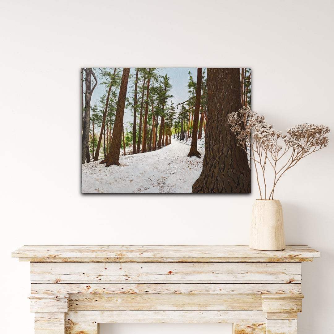 Framed print of a snowy forest scene on a wall above a wooden console table.