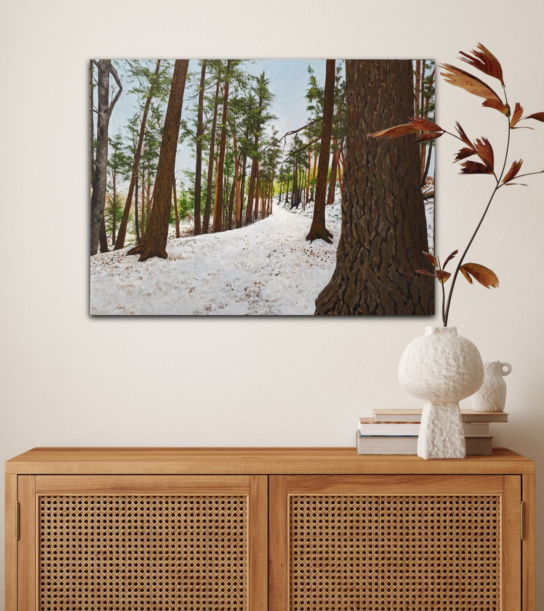 Framed forest scene above a wooden cabinet with decorative items.