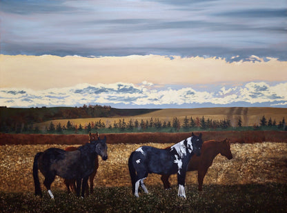 Horses standing in a field with a scenic background of trees and clouds.