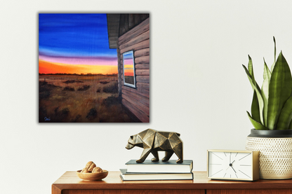 side table with books, a clock, plant and nuts, above hangs a landscape painting of a cabin at sunset