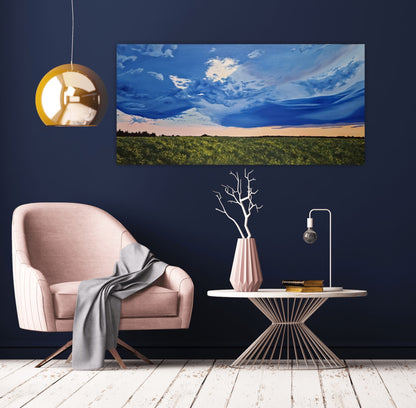 Golden Hour Affirmation is an original oil painting by Christina Gouldsborough of a vibrant stormy sky with a sunset over a canola field on a blue wall behind a gold lamp and pink chair